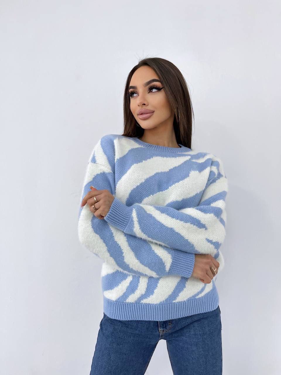 Woman wearing a blue and white patterned sweater against a plain background