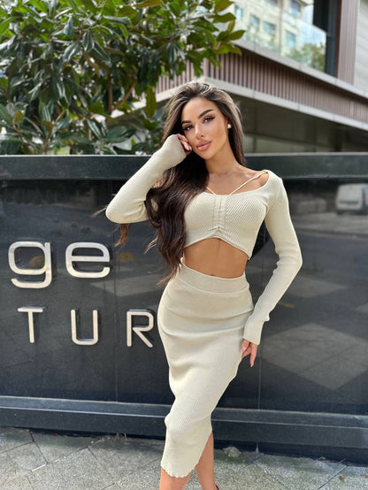 Woman in a beige outfit posing in front of a building with 'GE TUR' branding.