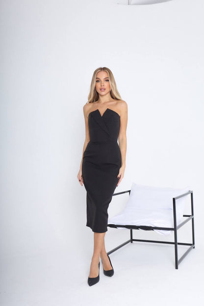 Woman wearing a black strapless dress standing against a white background