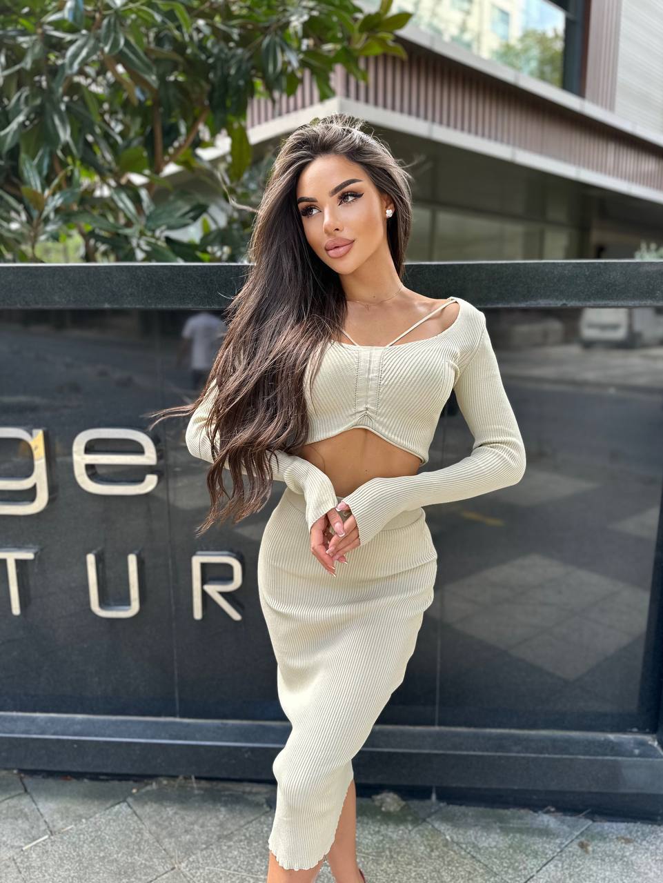 Woman in a white outfit standing in front of a building with 'Ritz Carlton' branding.