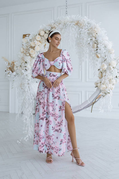 Woman in a floral dress standing in front of a decorative floral arch.