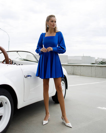 Woman in a blue dress standing next to a white car on a road.