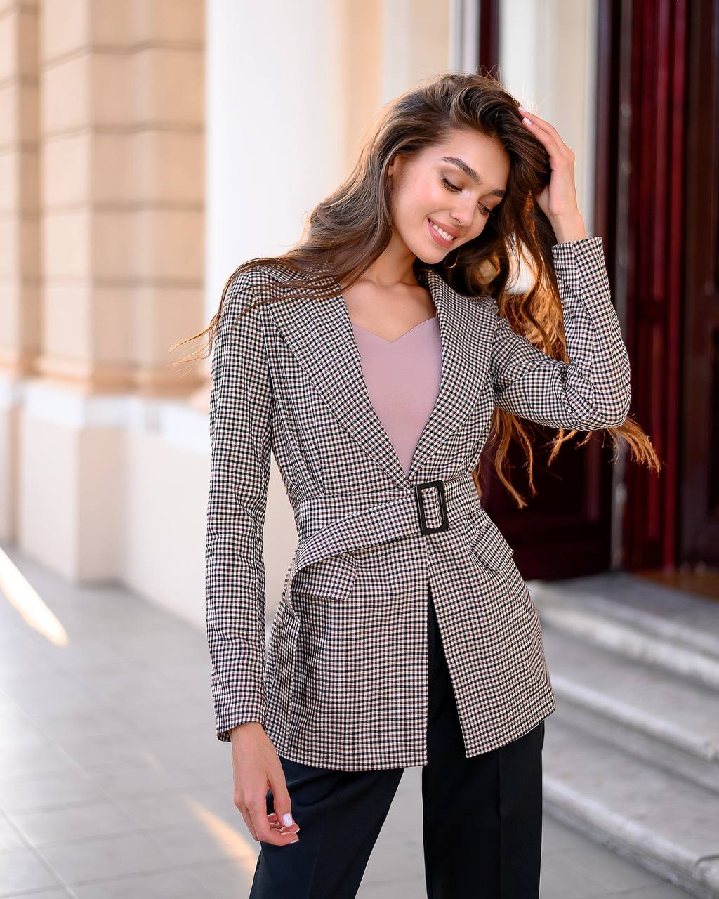 Woman wearing a checkered blazer with a belt in an urban setting