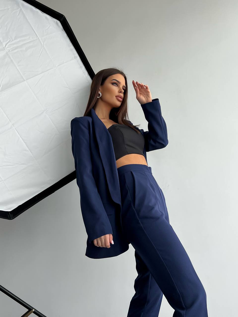 Woman in a navy blue outfit posing in front of a white background