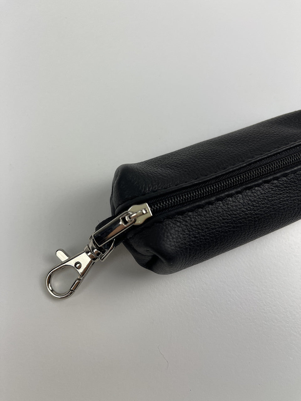 A black pebbled faux-leather zippered pouch with a silver metal lobster clasp, shown on a light gray background.