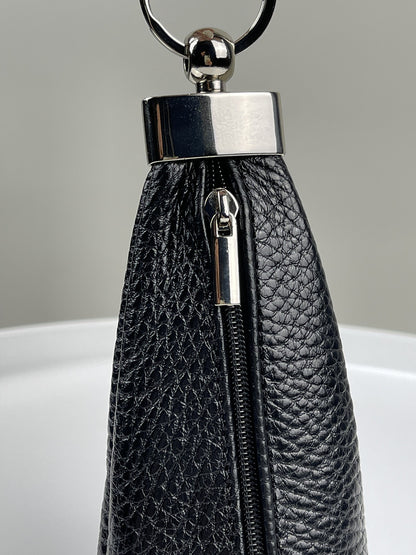 Close-up of a black pebbled leather zippered pouch or clutch with a polished silver-tone metal ring and bar clasp, shown against a neutral gray background.