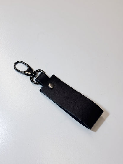A black leather keychain strap with a silver-tone metal lobster clasp and snap button, shown on a plain white background.