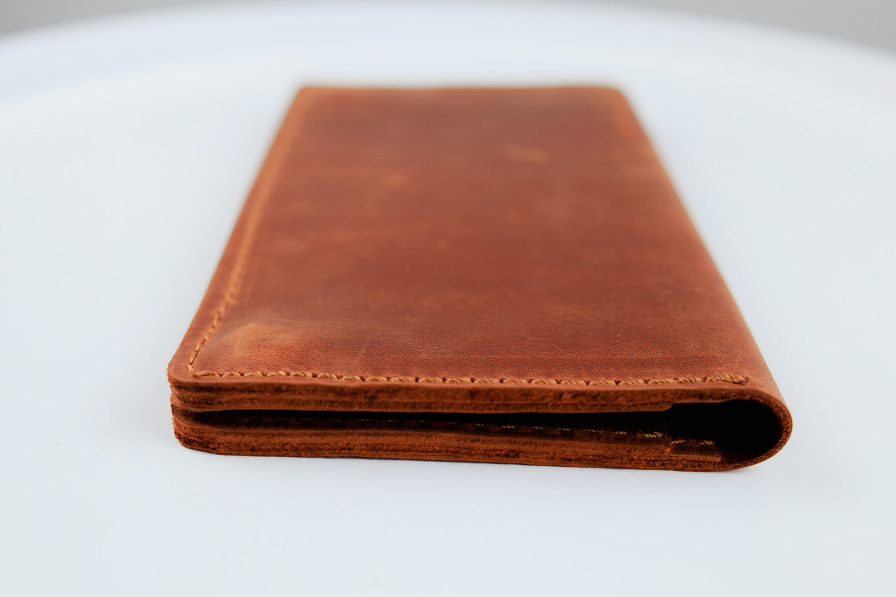 A brown leather wallet shown closed from the front, resting on a plain white surface.