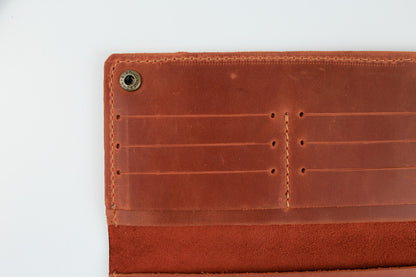 Close-up of the interior of a brown leather wallet or card holder, showing stitched card slots and a metal snap button on a white background.