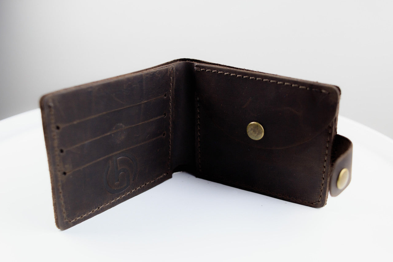 A dark brown leather bifold wallet shown open, displaying its interior card slots, stitching, and brass snap buttons, set against a clean white background.