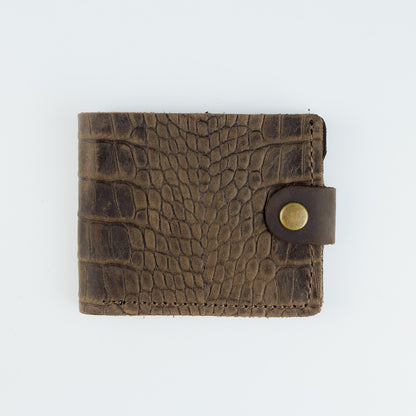 A brown leather bi-fold wallet with a crocodile-embossed texture and a snap-button closure, shown flat against a plain white background.