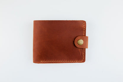 A brown leather bifold wallet with a snap-button closure, shown flat against a plain white background.