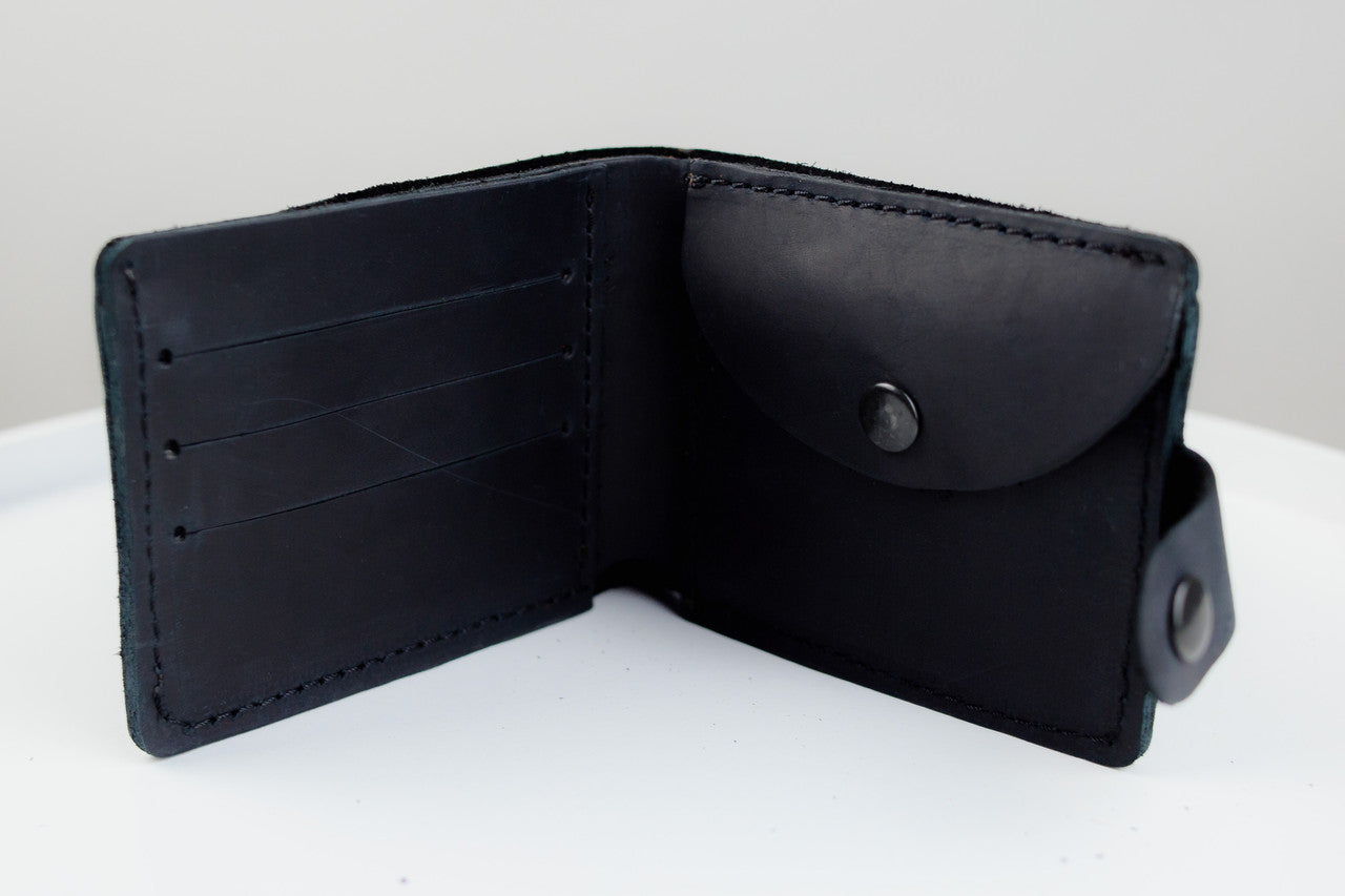 A black leather bifold wallet shown open, displaying its interior card slots, a snap-button pocket, and a small attached loop on a plain white surface.