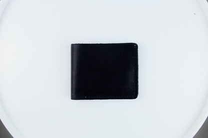 A black leather bifold wallet centered on a white circular surface.