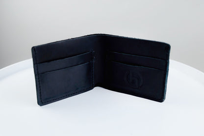 An open black leather bifold wallet with multiple card slots and a debossed logo on the inside, displayed on a white surface against a light gray background.