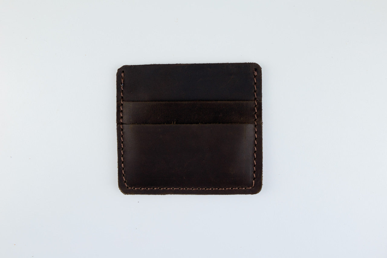 A dark brown leather card holder wallet with visible stitching, photographed flat against a plain white background.