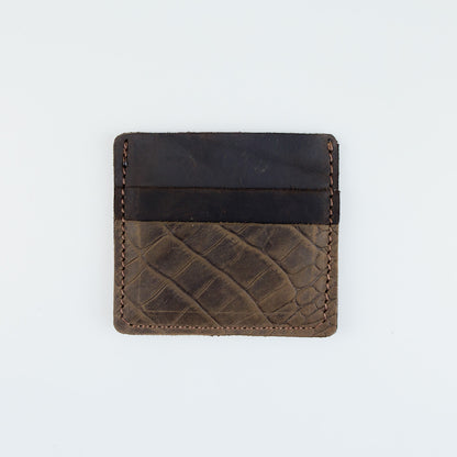 A minimalist card holder wallet made of dark brown leather with a textured crocodile pattern on the lower half and a smooth black leather band across the top, shown on a plain white background.