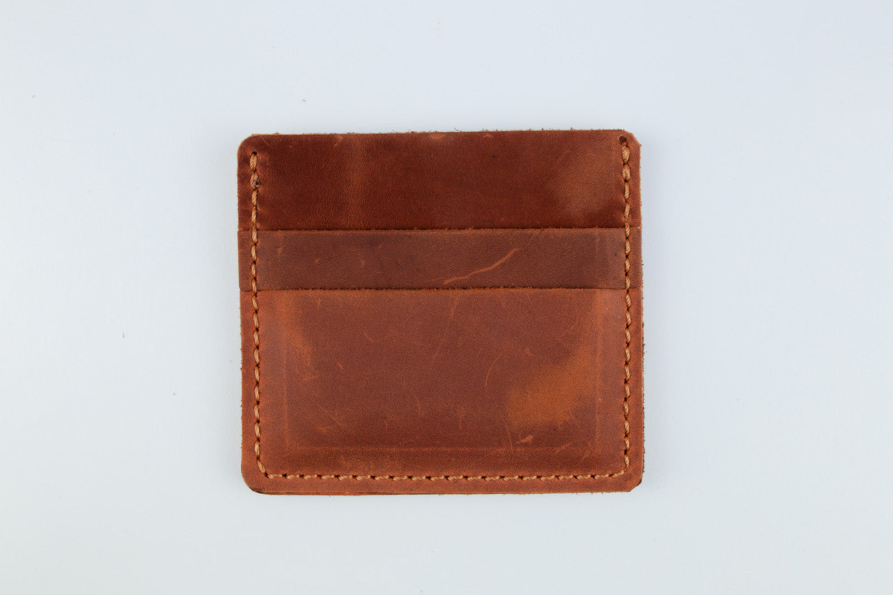 A brown leather card holder wallet with a stitched border and a horizontal slit pocket, shown on a plain white background.
