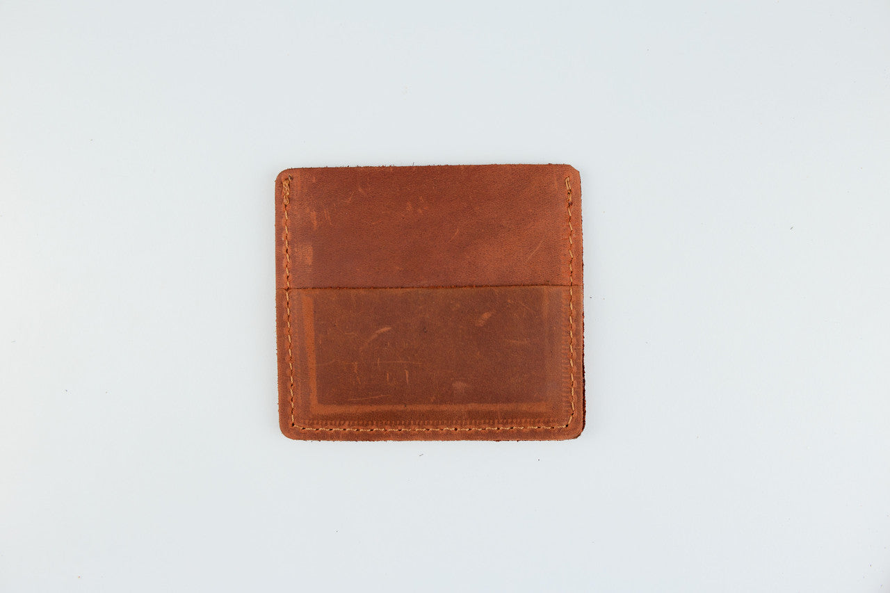 A brown leather card holder wallet with a stitched border, photographed flat against a plain white background.