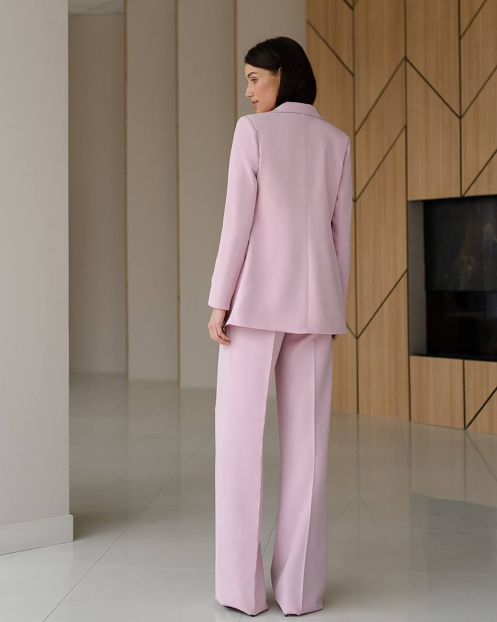 Woman in a pink suit standing in a modern interior setting.