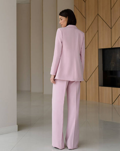 Woman in a pink suit standing in a modern interior setting.