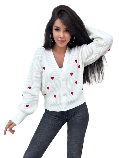 Woman wearing a white cardigan with red heart patterns on a white background