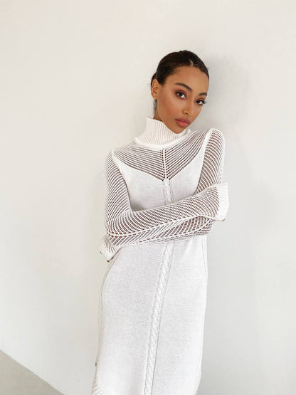Woman wearing a white dress with a textured shawl against a plain background