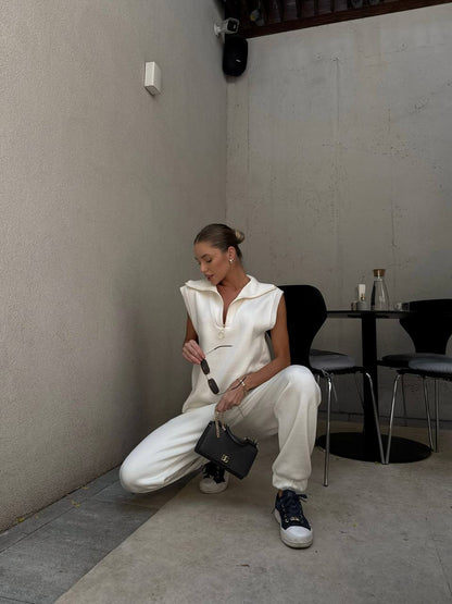 Woman in a white outfit sitting on the floor in a minimalistic room.