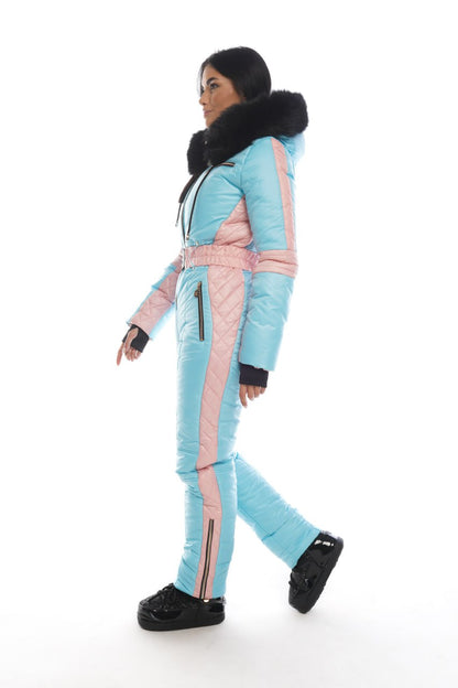 Person wearing a light blue and pink snowsuit with black accents on a white background