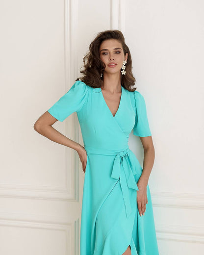 Woman wearing a turquoise dress against a white wall