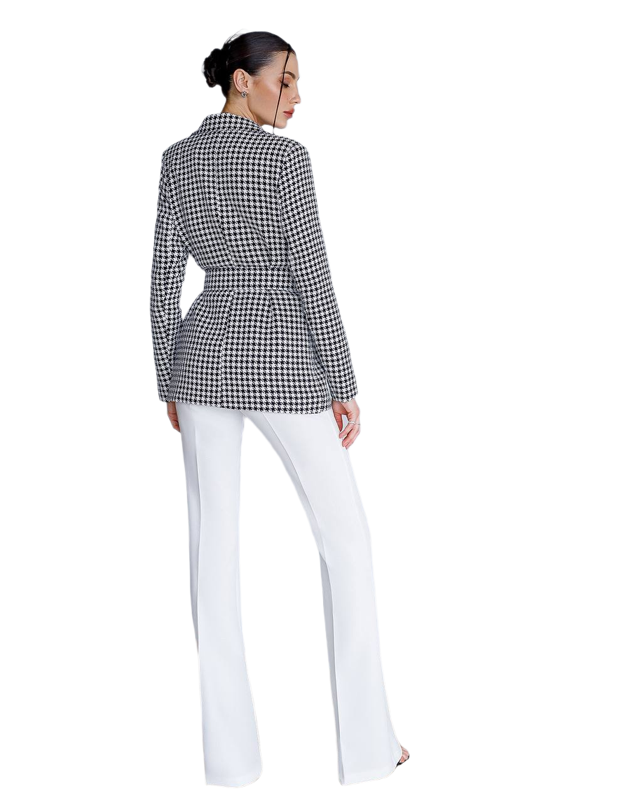 Person wearing a black and white checkered blazer and white pants on a white background