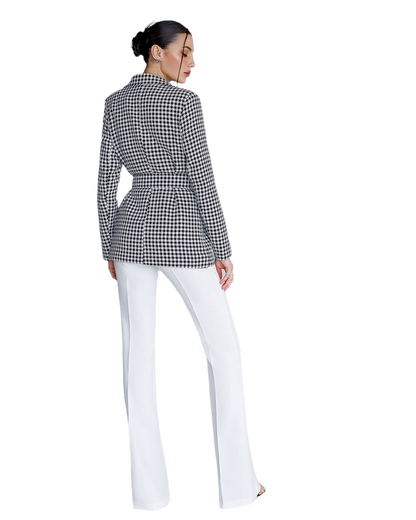 Person wearing a black and white checkered blazer and white pants on a white background