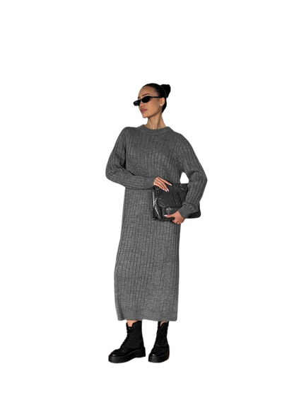 Woman wearing a gray ribbed dress holding a black clutch against a white background