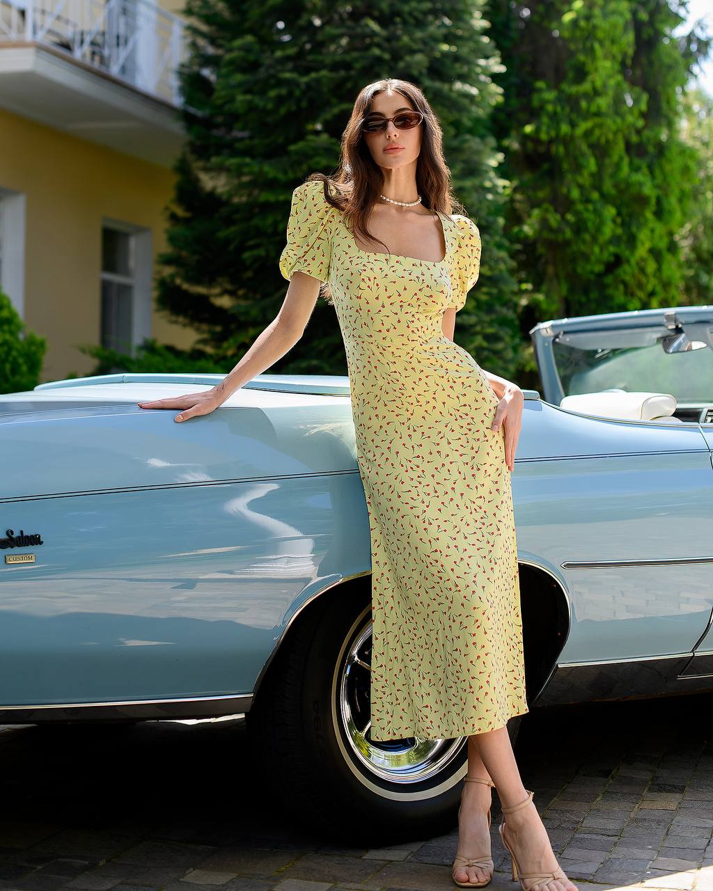 Woman in a yellow dress standing next to a vintage car