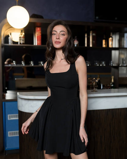 Woman in a black dress standing in a bar setting