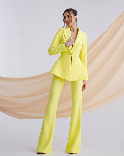 Woman wearing a bright yellow suit with a flowing beige fabric in the background