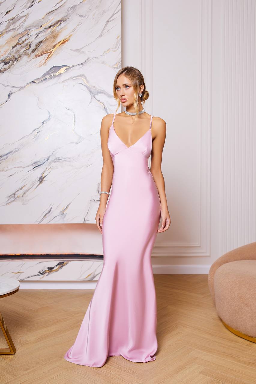 Woman wearing a pink evening gown in an elegant room with marble wall.