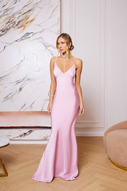 Woman wearing a pink evening gown in an elegant room with marble wall.