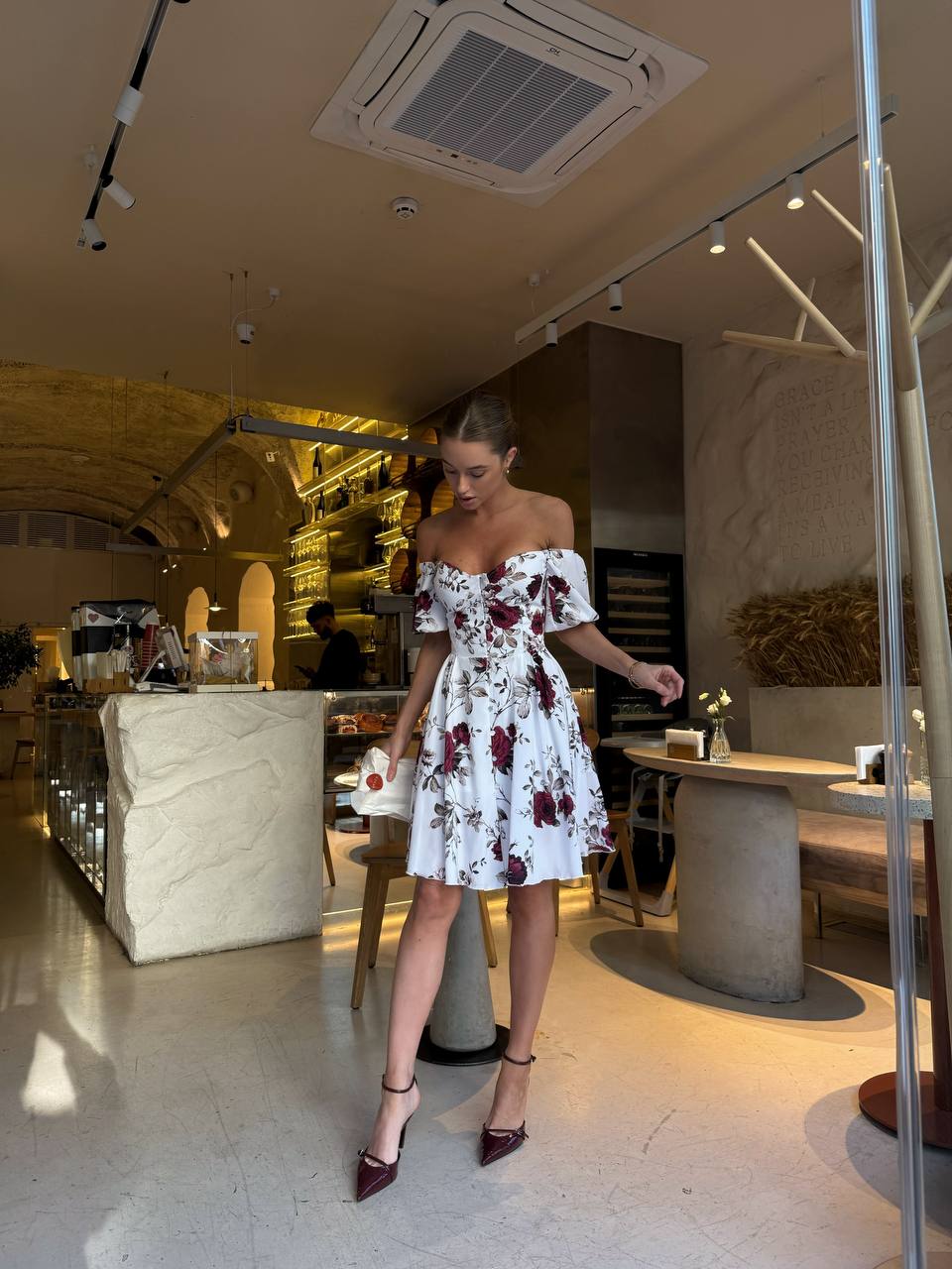 Woman in a floral dress standing in a modern interior setting