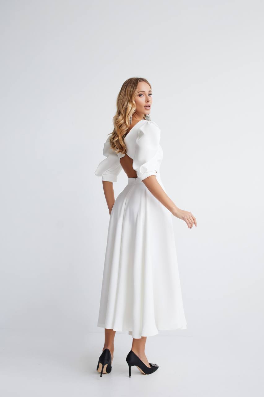 Woman wearing a white dress with puffed sleeves on a white background