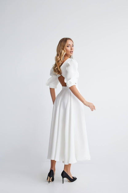 Woman wearing a white dress with puffed sleeves on a white background