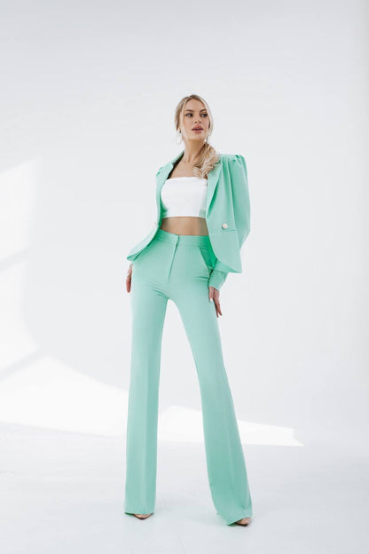 Woman wearing a mint green suit with a white top on a white background