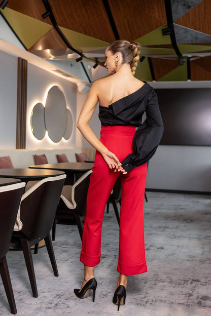 Woman in a black top and red pants standing in a modern restaurant.