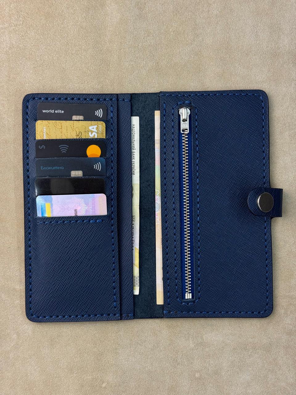 A navy blue leather wallet shown open, displaying its interior compartments including card slots with sample credit cards, a zipper pocket, and a snap-button closure, set against a neutral beige background.