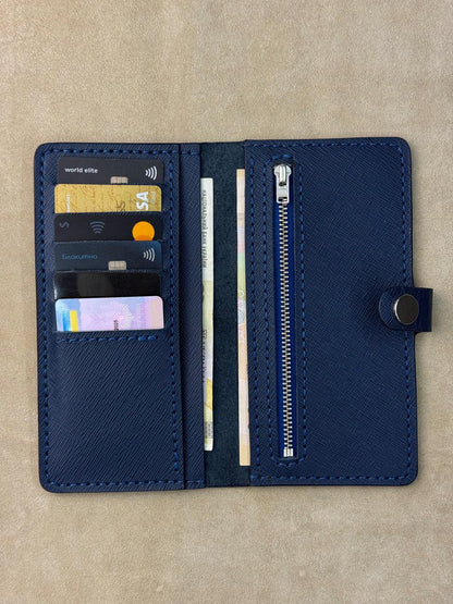 A navy blue leather wallet shown open, displaying its interior compartments including card slots with sample credit cards, a zipper pocket, and a snap-button closure, set against a neutral beige background.