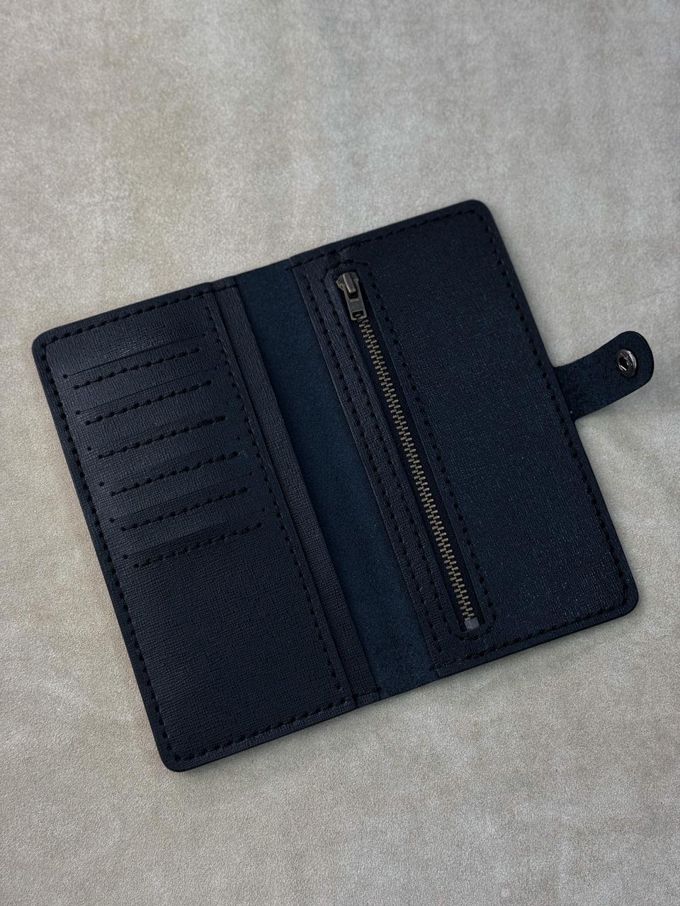 A dark navy blue leather wallet shown open, displaying its interior features including card slots, a central zipper pocket, and a small tab closure, set against a textured light gray background.