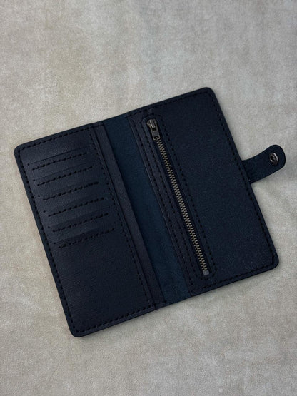 A dark navy blue leather wallet shown open, displaying its interior features including card slots, a central zipper pocket, and a small tab closure, set against a textured light gray background.