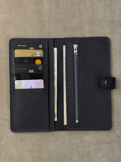A black textured leather wallet shown open, displaying its interior compartments including card slots with sample credit cards, a vertical card slot, a zipper pocket, and a snap-button closure, set against a neutral textured background.