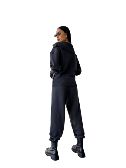 Person wearing a black hoodie and pants on a white background