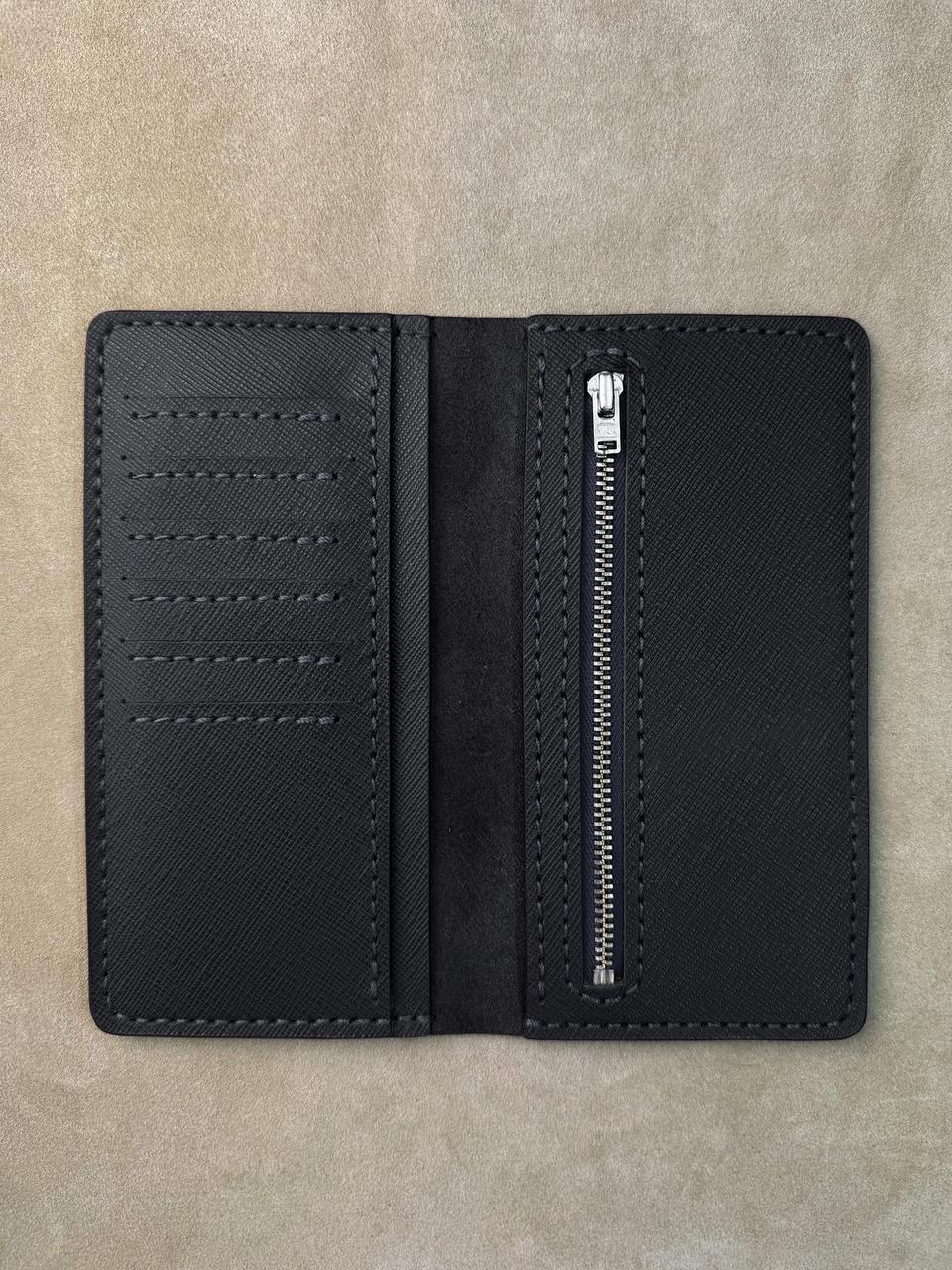 A black textured leather wallet shown open, featuring multiple card slots on the left and a vertical zippered pocket on the right, photographed flat on a neutral beige textured background.
